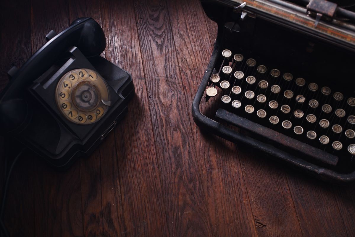 Old retro phone with vintage typewriter on wooden table