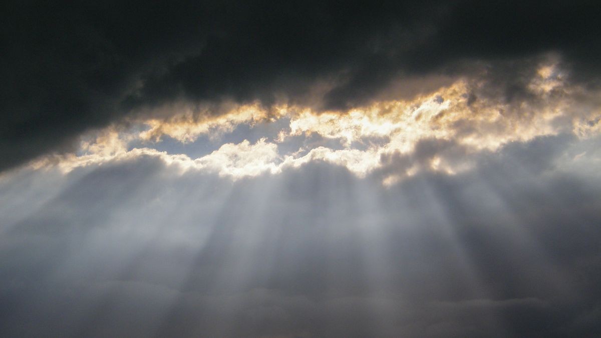 Impressive sunshine. Shine. Light. Hole in the clouds. The rays of the sun slide through the dark clouds. Beautiful sunlight through opening gap in cloudy sky